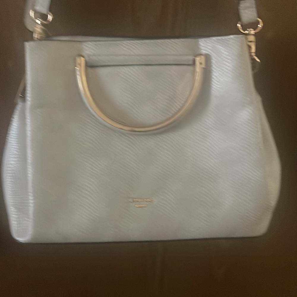 Cream colored purse. Has detachable shoulder strap. Three big pockets.
